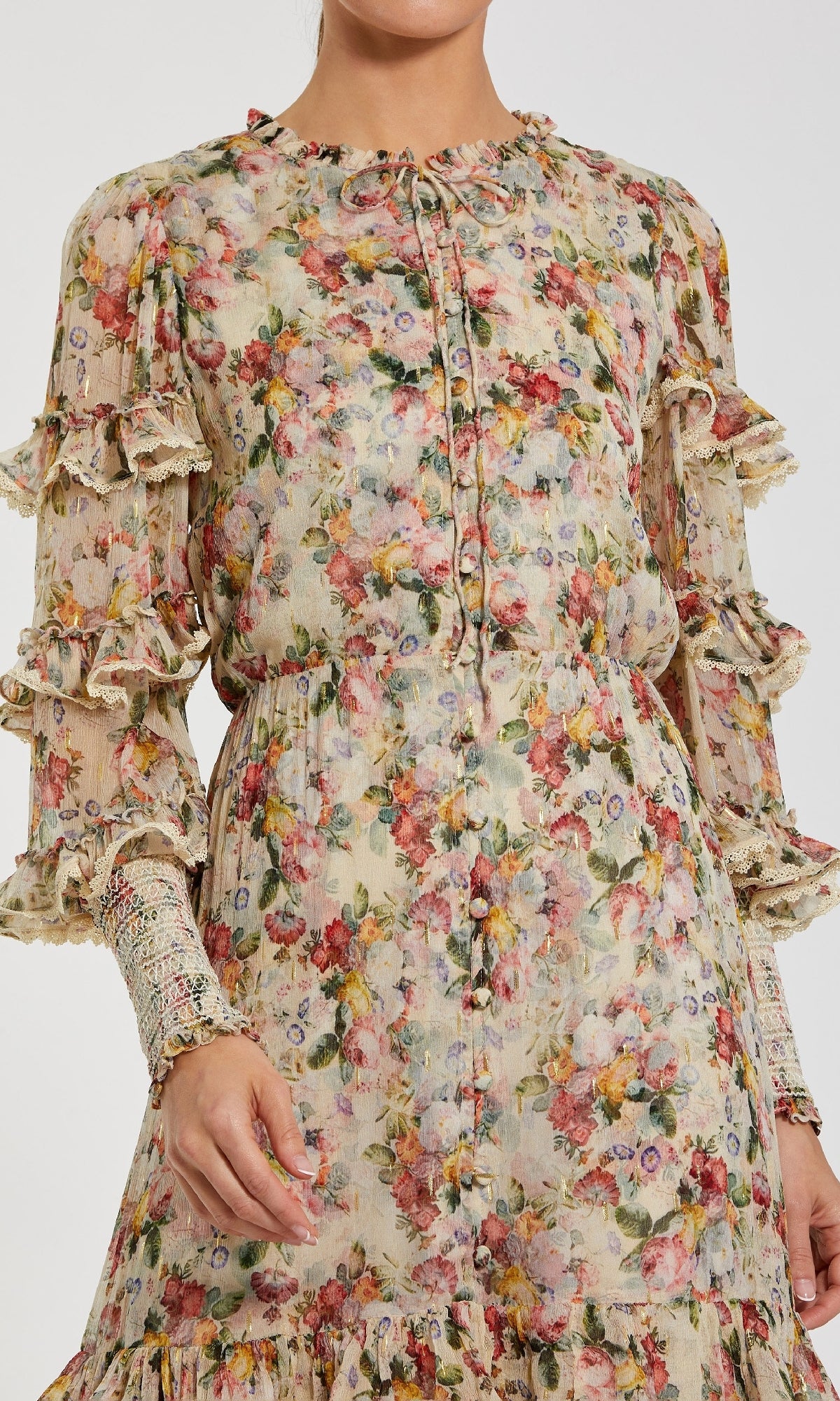 A person wearing the Mac Duggal 8334 Long Sleeve Ruffle Formal Dress, featuring floral print, ruffled sleeves, and lace trim, shown from shoulders to knees.